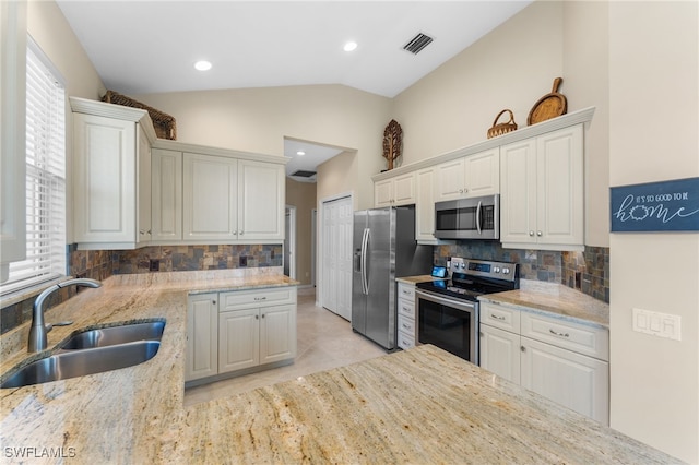 kitchen with light stone counters, appliances with stainless steel finishes, sink, and white cabinets