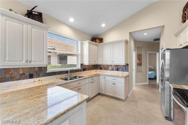 kitchen featuring vaulted ceiling, white cabinetry, sink, stainless steel appliances, and light stone countertops