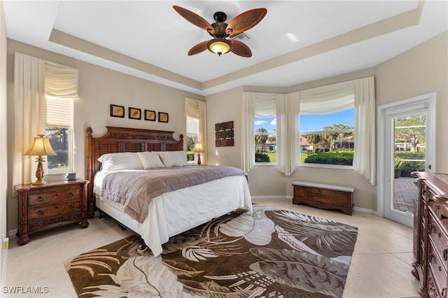 bedroom with light tile patterned flooring, ceiling fan, a raised ceiling, and access to outside