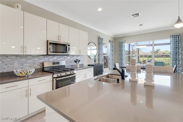 kitchen with decorative light fixtures, tasteful backsplash, sink, white cabinets, and stainless steel appliances