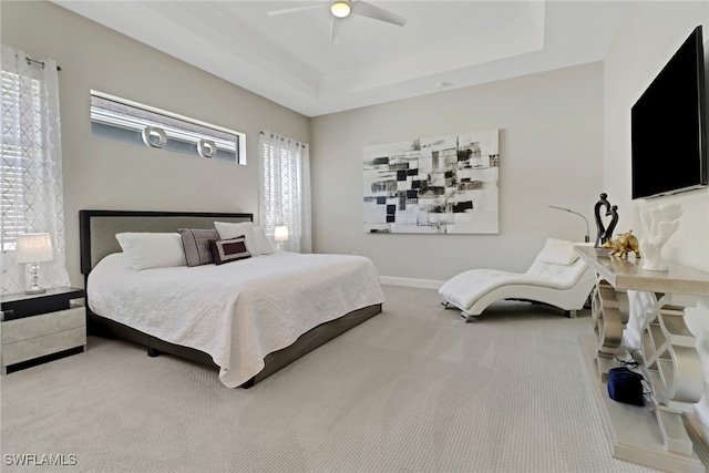 bedroom with a raised ceiling, ceiling fan, and carpet