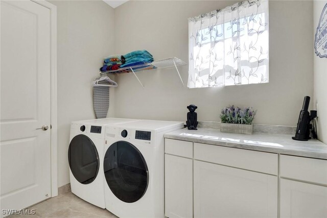 clothes washing area featuring cabinets and washer and clothes dryer