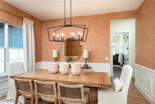 dining room featuring a chandelier, wainscoting, and wallpapered walls