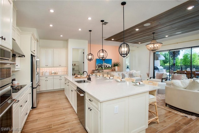 kitchen with open floor plan, light countertops, a center island with sink, and hanging light fixtures