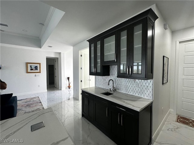 kitchen with sink, crown molding, backsplash, light stone counters, and a tray ceiling