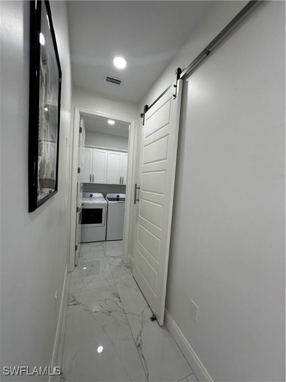 hall with a barn door and independent washer and dryer