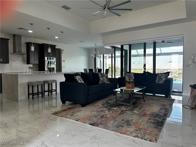 living room featuring crown molding and ceiling fan with notable chandelier