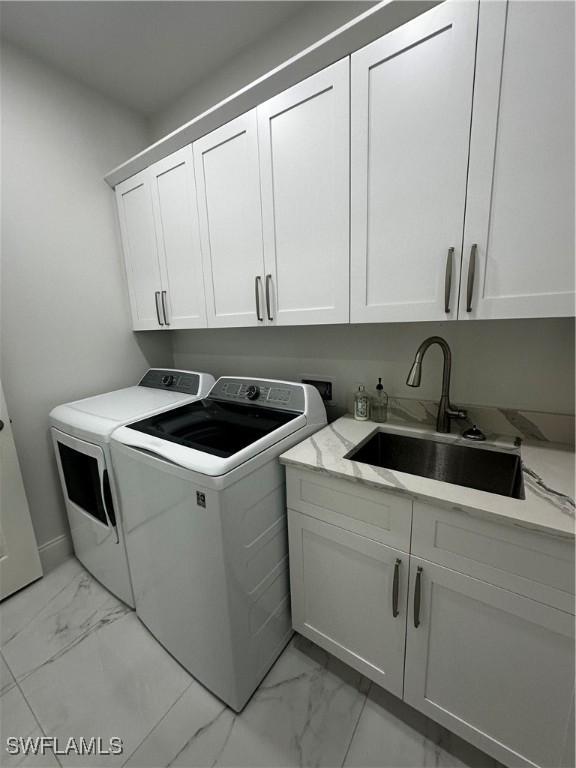 washroom with cabinets, independent washer and dryer, and sink