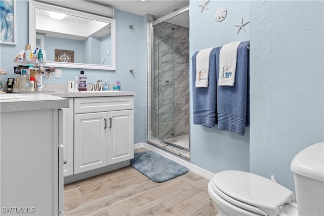 bathroom with a shower with door, vanity, hardwood / wood-style floors, and toilet