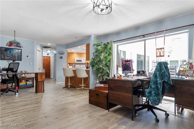 office with light hardwood / wood-style flooring and a textured ceiling