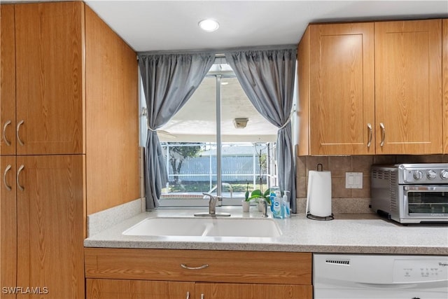 kitchen featuring tasteful backsplash, dishwasher, and sink