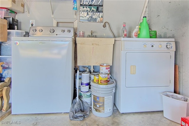 clothes washing area with washing machine and dryer and sink