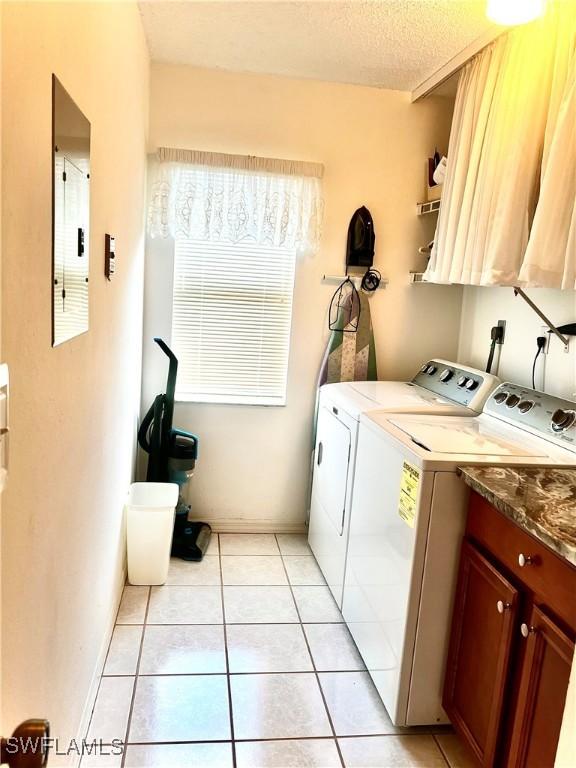 laundry area with cabinets, electric panel, washer and clothes dryer, and light tile patterned floors