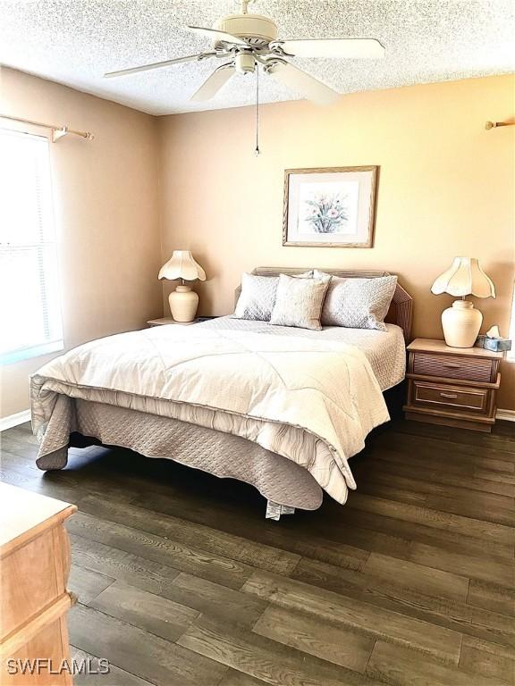 bedroom with ceiling fan, dark hardwood / wood-style floors, and a textured ceiling