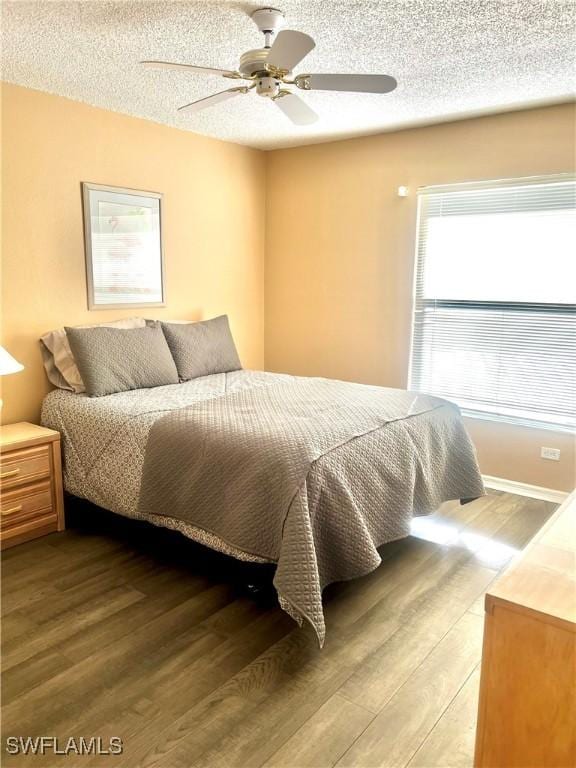 bedroom featuring ceiling fan, hardwood / wood-style flooring, and a textured ceiling