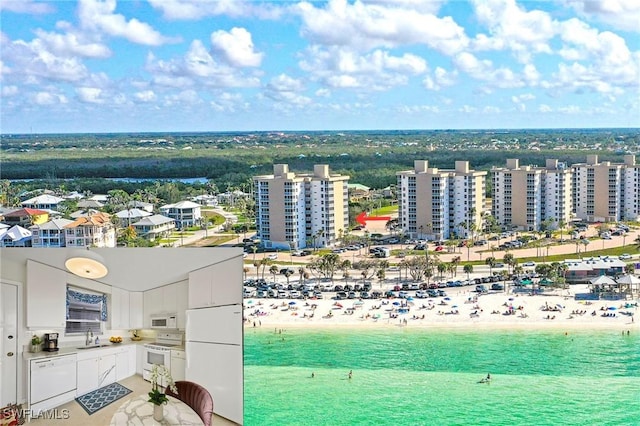 birds eye view of property featuring a water view and a beach view