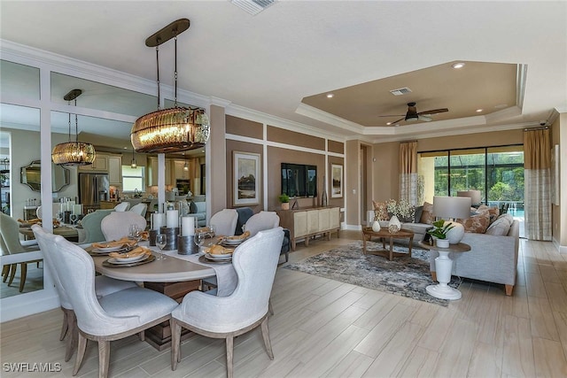 dining room featuring visible vents, ornamental molding, a raised ceiling, and light wood-style flooring