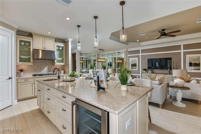 kitchen featuring wine cooler, a center island with sink, glass insert cabinets, open floor plan, and under cabinet range hood