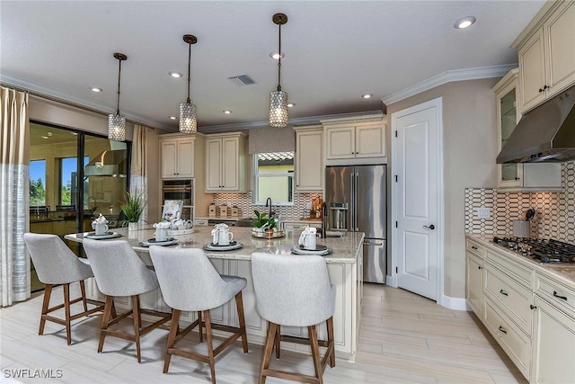 kitchen featuring hanging light fixtures, cream cabinets, a kitchen island, and stainless steel appliances