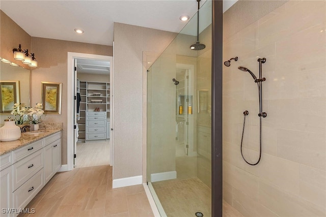 full bathroom with a walk in closet, vanity, and a walk in shower