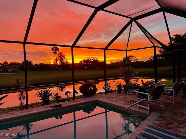 pool at dusk with a patio and a lanai