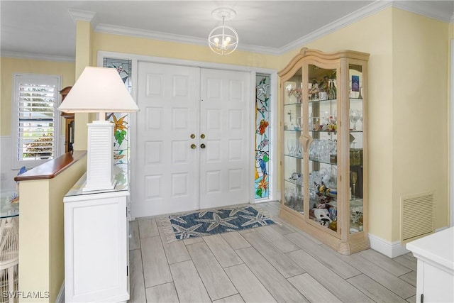 entrance foyer featuring wood tiled floor, visible vents, and ornamental molding