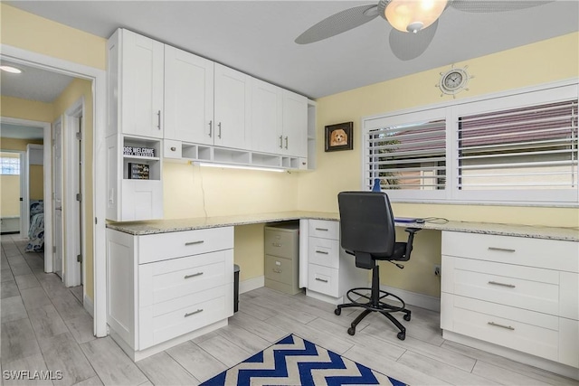 home office with a ceiling fan, wood finish floors, built in study area, and baseboards