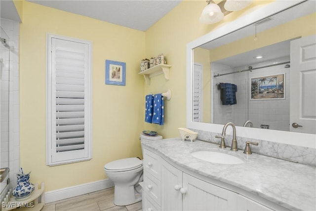 full bath featuring visible vents, toilet, vanity, tiled shower, and baseboards