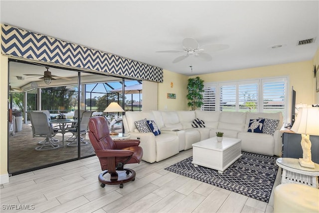 living room featuring a sunroom, visible vents, plenty of natural light, and ceiling fan