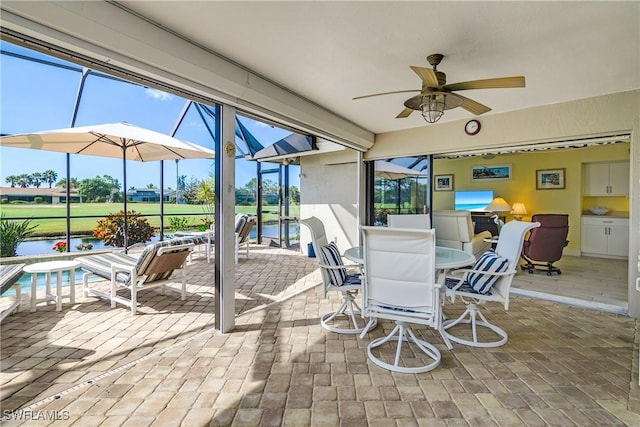 sunroom / solarium featuring a water view and ceiling fan