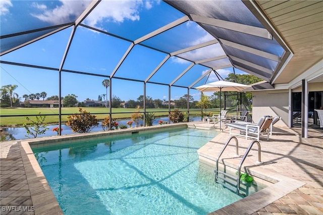 outdoor pool with glass enclosure, a patio area, and a water view