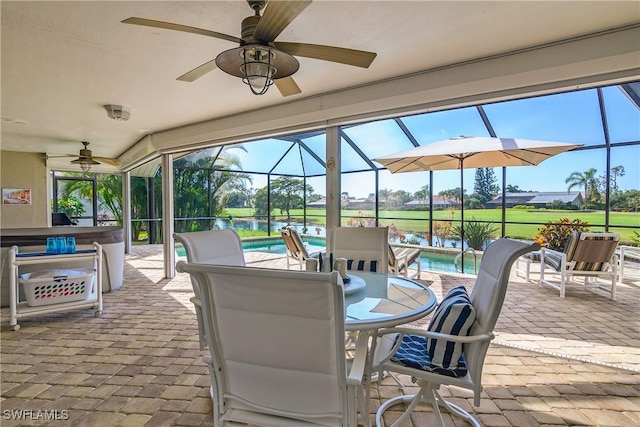 view of patio with glass enclosure, outdoor dining space, a ceiling fan, and an outdoor pool