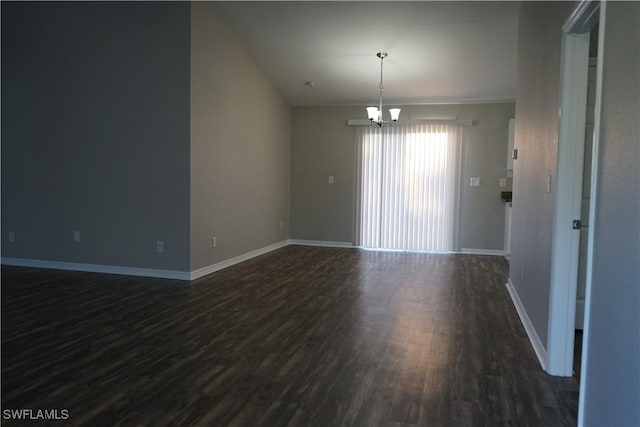 spare room with dark hardwood / wood-style flooring and a notable chandelier