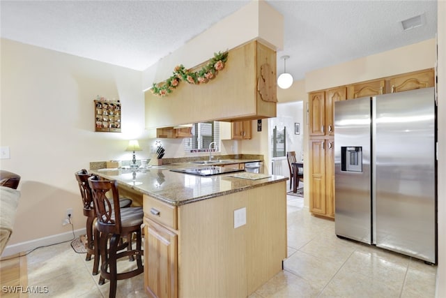 kitchen with pendant lighting, appliances with stainless steel finishes, light stone counters, a kitchen bar, and kitchen peninsula