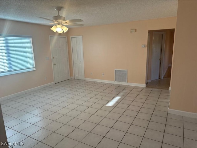 tiled empty room featuring ceiling fan and a textured ceiling