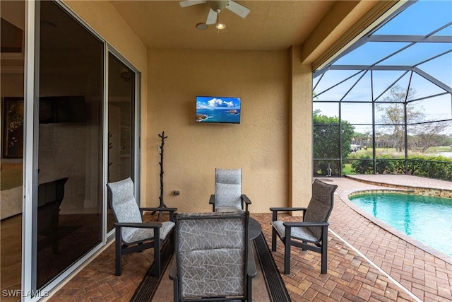 view of swimming pool with ceiling fan, a lanai, and a patio area