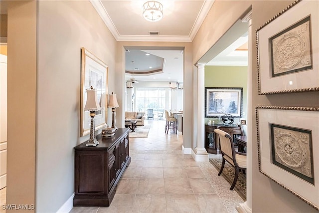 hall with ornate columns, ornamental molding, a raised ceiling, and light tile patterned floors