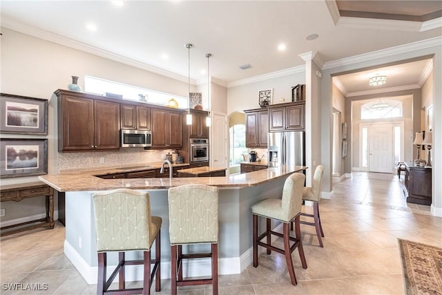 kitchen with pendant lighting, appliances with stainless steel finishes, a breakfast bar, and a large island with sink