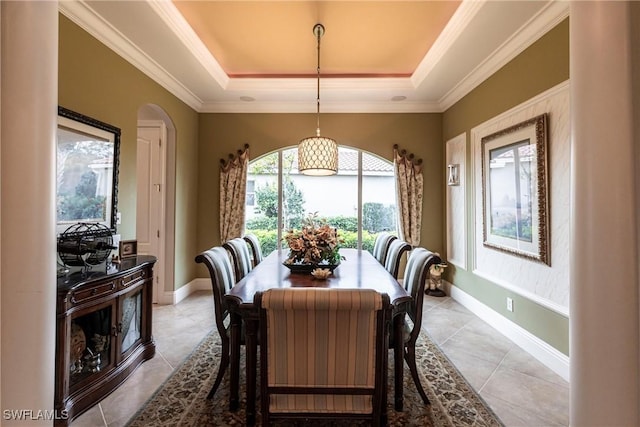 dining area featuring a raised ceiling, ornamental molding, and light tile patterned floors