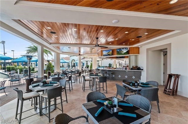 tiled dining space featuring ceiling fan, ornamental molding, a tray ceiling, and wooden ceiling