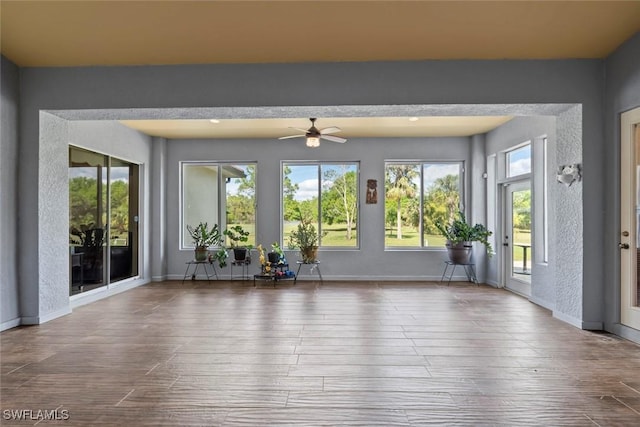 unfurnished sunroom with ceiling fan