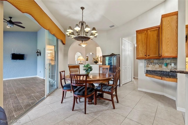 dining room featuring ceiling fan with notable chandelier, vaulted ceiling, and light tile patterned flooring