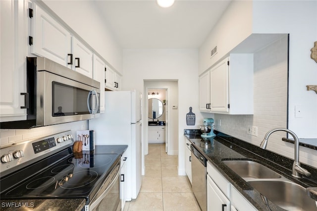 kitchen featuring sink, stainless steel appliances, white cabinetry, and dark stone counters