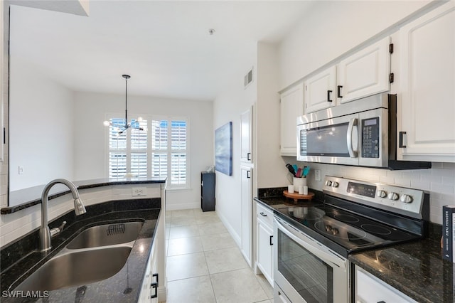 kitchen featuring sink, stainless steel appliances, white cabinetry, and dark stone countertops