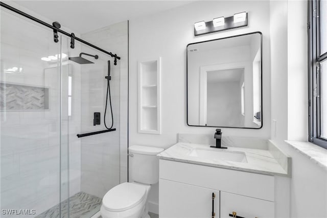 bathroom with vanity, toilet, and a shower with door