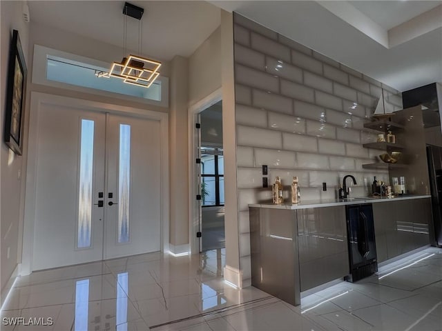 interior space with french doors, decorative light fixtures, sink, and backsplash