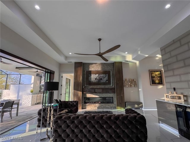 tiled living room featuring ceiling fan and a large fireplace