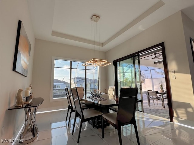 dining area with a raised ceiling and light tile patterned floors