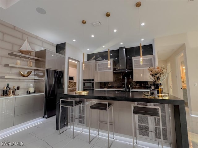 kitchen with black refrigerator, wall chimney range hood, oven, and hanging light fixtures