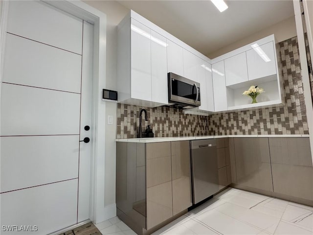 kitchen with tasteful backsplash, white cabinetry, appliances with stainless steel finishes, and sink